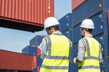 Logistics engineer and inspector working togetter and discussing in shipping containerin commercial transport port
