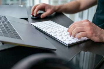 Obraz na płótnie Canvas デスクに向かってキーボードをタイピングする男性の手