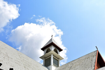 Church Roof with a cross. Church building roof with holy cross. Cloudy moody blue sky background. Minimal architecture design and detail. Exterior design and detail. Abstract architecture.
