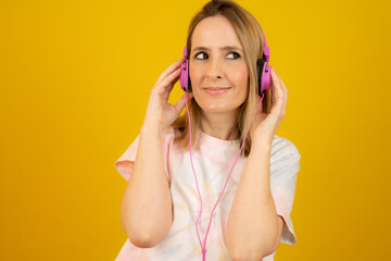 Naklejka premium Close up portrait of young woman in headphones smiling broadly isolated over yellow background.