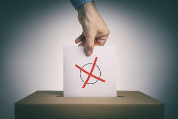 Wähler wirft Stimmzettel mit Kreuz in eine Wahlurne