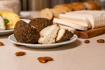Cheese sprinkled with spices in the foreground. Homemade goat cheese and curd cheese served for breakfast. Organic dairy products. 