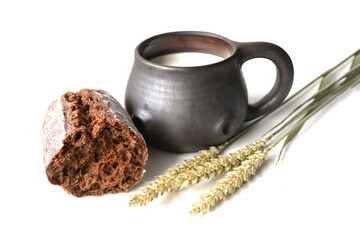 Fresh cow's milk in a ceramic mug,  grain bread and three bread spikelets on a white background. Morning breakfast. Healthy and ecological food.