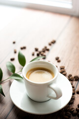 Cup of hot coffee on wooden table, surrounded by coffee beans