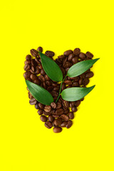 Obraz premium Coffee beans in the shape of a heart on a yellow background.