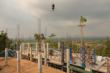 Concrete columns in the building construction area in the clouds and the mountains distant.