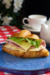 croissant with ham and cheese for breakfast close-up on a blue plate restaurant serving. High quality photo