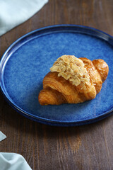 croissant with almond flakes on a blue plate high quality. High quality photo