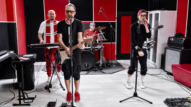 Modern music group at rehearsal base, recording track album