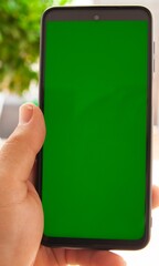 Naklejka premium hand holding a smartphone with green screen