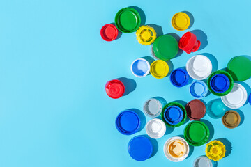 Colorful plastic bottle caps on a blue background, collecting plastic for recycling and reuse. copy space