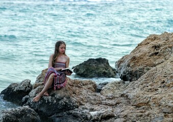 Fototapeta na wymiar woman is sitting on rocks and reading a book 