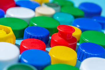 Colorful plastic bottle caps on a blue background, collecting plastic for recycling and reuse.
