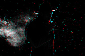 dark silhouette of a man in a hat Smoking a cigarette in the rain