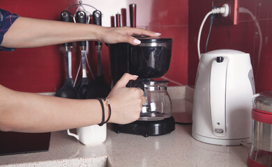 Woman making coffee in a coffee maker machine.