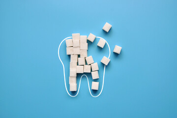 Sugar cubes in the silhouette of the tooth. The harm of sugar and sweets to the teeth, the development of caries