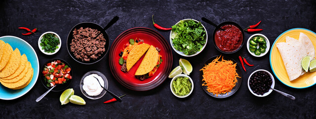Taco bar table scene with a selection of ingredients. Top view on a dark slate banner background....