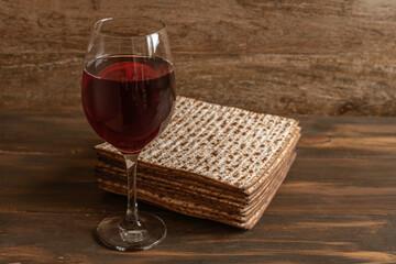 Glass of wine and matzah bread for Jewish holiday Pesach over dark wooden background. 