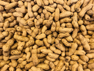 A large pile of unpeeled peanuts in the skin. Nuts natural background