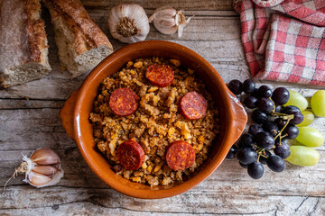 Migas Manchegas with chorizo in a clay pot, served with grapes, garlic and bread. It is a Spanish dish, traditional from Castilla la Mancha.