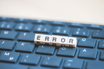 Error or bug concept: Wooden cubes with letters “Error” lying on a laptop, concept for computer...
