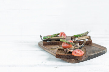 Shprots Sandwich with tomato and asparagus over rustic background with copy space.