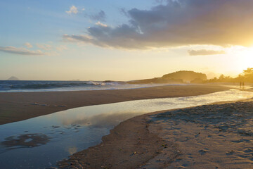 beautiful sunset at Piratininga beach, Niter&oacute;i, overlooking the hills of Rio de Janeiro. Silhouette of some people on the beach. Sunny summer day.