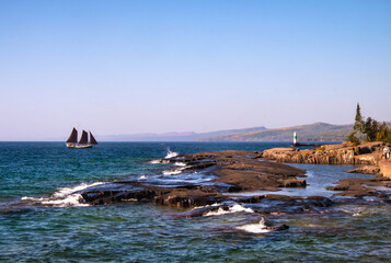 A traditional sailboat on Lake Superior sails into the harbor of Grand Marais, Minnesota, USA