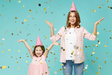 Happy woman in pink clothes birthday hat have fun child baby girl 5-6 years old. Mom little kid daughter raised up hands celebrate isolated on blue background studio. Mother's Day love family concept.