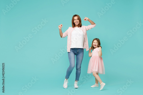 Full length happy woman in pink clothes have fun with cute child baby girl 5-6 years old. Mommy little kid daughter dancing isolated on pastel blue background studio. Mother's Day love family concept.
