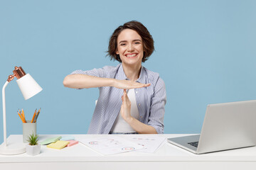 Young happy successful employee business woman in casual shirt sit work at white office desk with pc laptop hold stop gesture hands perpendicularly isolated on pastel blue background studio portrait