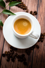 Cup of hot coffee on wooden table, surrounded by coffee beans