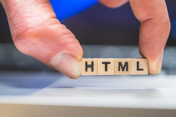 HTML web language: Wooden cubes with letters “HTML” lying on a laptop, concept for HTML