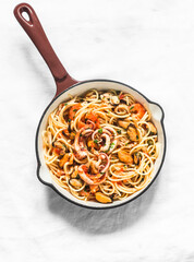 Spaghetti frutti di mare in cooking pan on a light background, top view. Delicious traditional mediterranean food