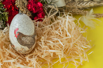 Colorful Easter egg on a yellow background with a painted rooster and easter palm