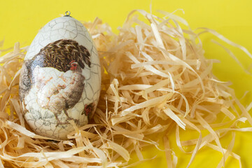 Colorful Easter egg on a yellow background with a painted hen 