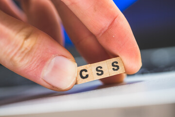 CSS web language: Wooden cubes with letters “CSS” lying on a laptop, concept for style sheet language