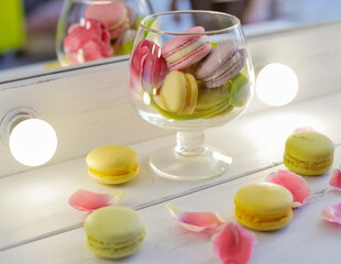 Macarons and flowers on a white background. Colorful french dessert with fresh flowers. Top view
