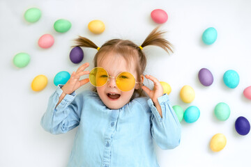 Fototapeta na wymiar Portrait of a child in yellow sunglasses on a white background with Easter eggs