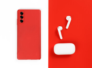 Red smart phone and white wireless earphones