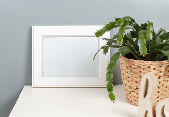 Front view of white poster frame mockup with  plant in a pot