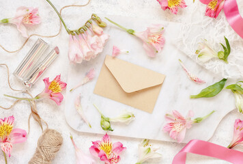 Beige envelope on a white table between pink flowers