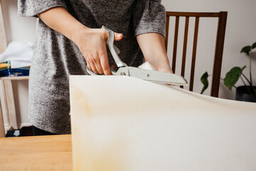 Young adult woman cutting chunk of foam rubber