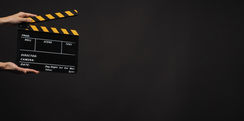 Fototapeta na wymiar Hand's holding yellow and black Clapperboard or movie slate use in video production ,film, cinema industry on black background.