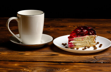 white coffee cup with a piece of cherry cake on a wooden table