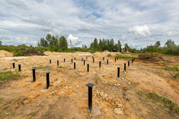 Iron screw piles in the ground for a new building on construction site.