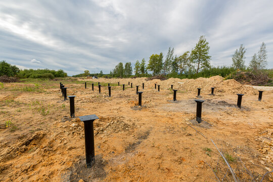 Iron screw piles in the ground for a new building on construction site.