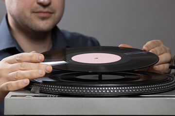 A man and vintage record player while recording, the record spins and music plays. Gramophone and antiquity idea