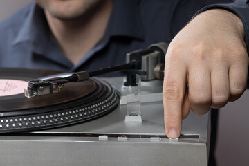 A man presses a gramophone vinyl record player button. Vintage record player spins