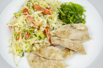diet dish on a plate with fresh salad with cabbage, tomatoes, greens and chicken breast